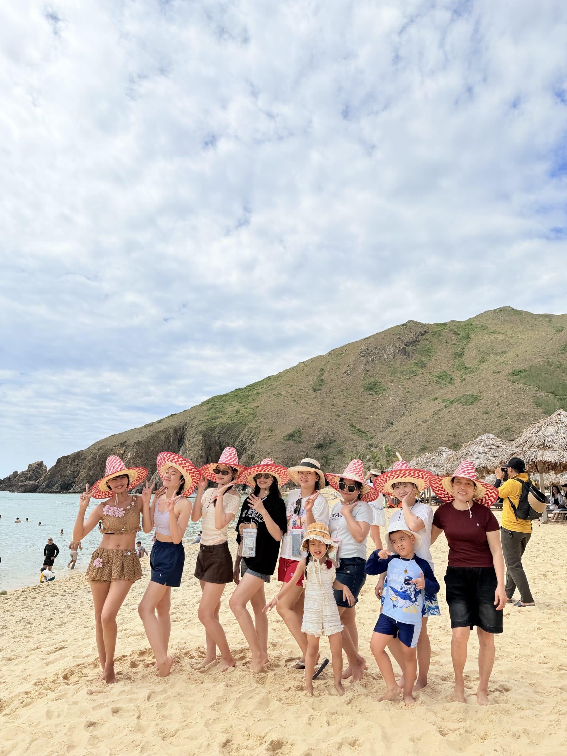 Team Art Spa Hoi An khám phá Quy Nhơn 2026 – Hành trình gắn kết đáng nhớ 11 Đội ngũ Art Spa Hoi An đội nón đỏ bên bãi biển và núi Kỳ Co